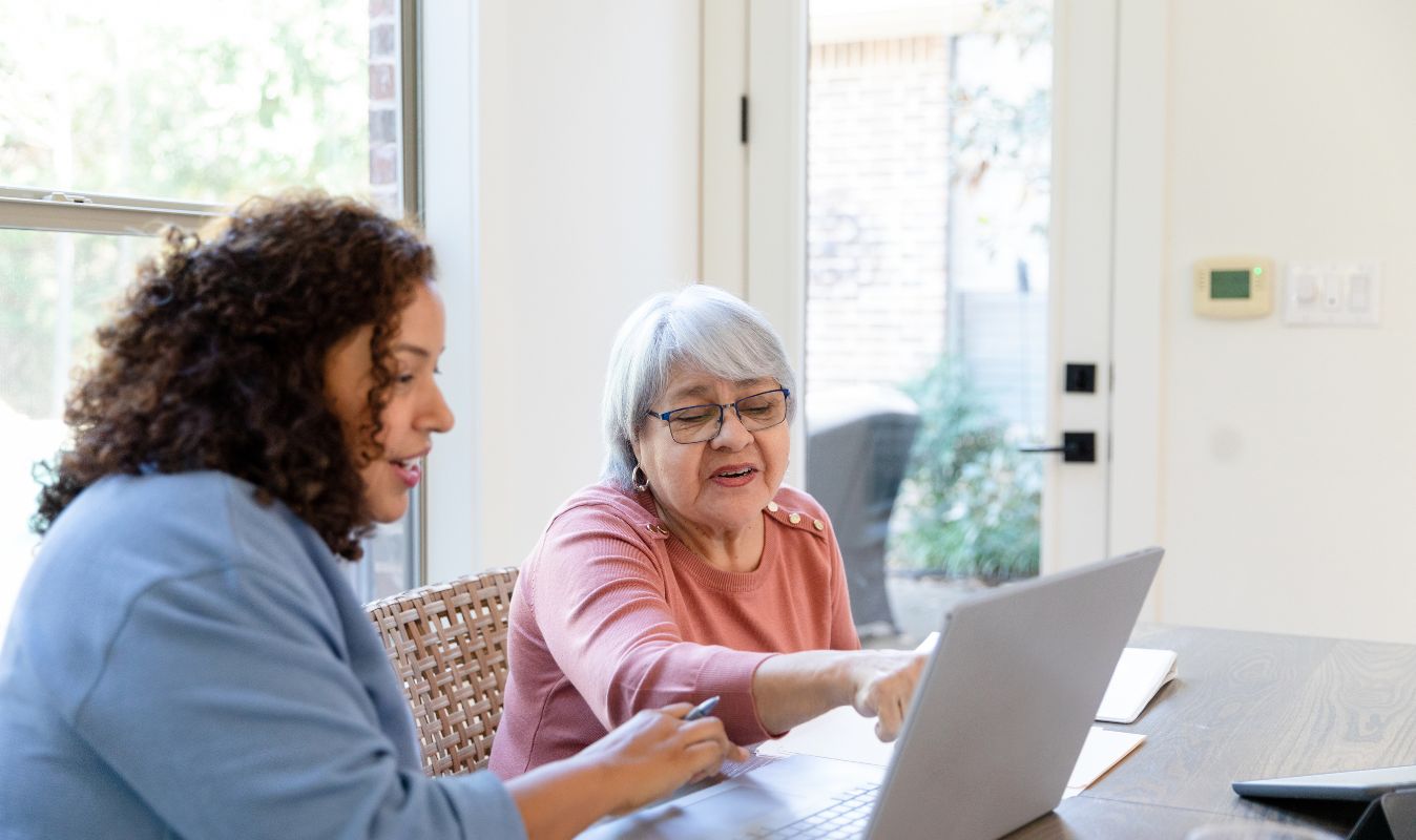 Teilnehmerin unterstützt Seniorin am Laptop