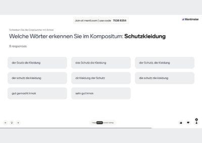 Ein junger Mann sitzt an einem Holztisch und hält ein Tablet in den Händen. Auf dem Bildschirm ist eine bunte Lern-App mit spielerischen Grafiken zu sehen, die Abkürzungen von Flughäfen anzeigen.
