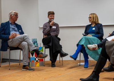 Drei Personen stehen im Gespräch in einem Veranstaltungsraum.