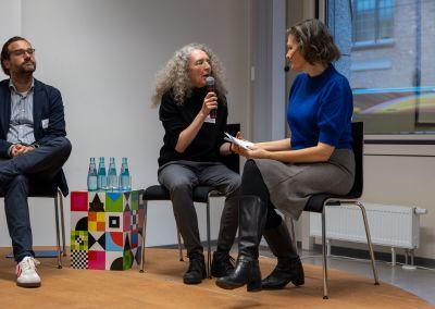 Zwei Personen unterhalten sich bei einer Kaffeepause, beide halten Tassen in der Hand.