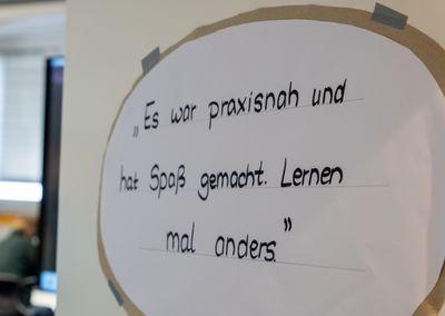 Ein Schild mit handgeschriebenem Zitat: „Es war praxisnah und hat Spaß gemacht. Lernen mal anders.“