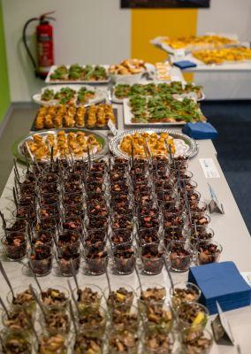 Ein reichhaltiges Buffet mit verschiedenen Häppchen und Desserts steht auf mehreren Tischen bereit.