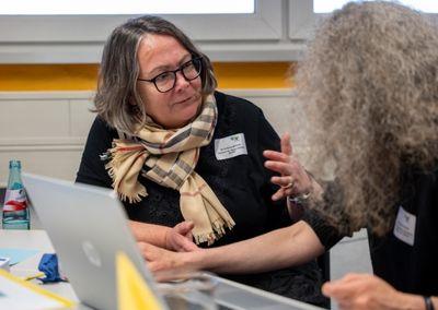 Eine Person hält ein Tablet und testet eine digitale Lernanwendung mit einem Sonnensymbol auf dem Bildschirm.