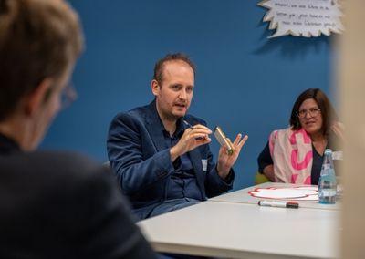 Eine Person hält ein Tablet und testet eine digitale Lernanwendung mit einem Sonnensymbol auf dem Bildschirm.