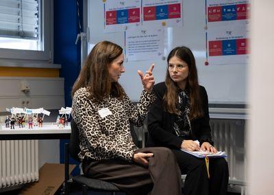 Zwei Personen betrachten eine Wand mit Fotos, Texten und QR-Codes aus dem Projekt #ABCforJobs.