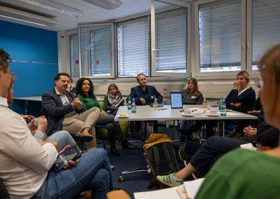 Eine Person hält ein Tablet und testet eine digitale Lernanwendung mit einem Sonnensymbol auf dem Bildschirm.