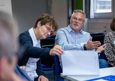 Eine Person hält ein Tablet und testet eine digitale Lernanwendung mit einem Sonnensymbol auf dem Bildschirm.