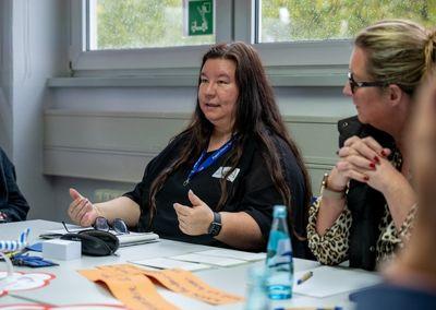 Drei Personen stehen im Gespräch in einem Veranstaltungsraum.