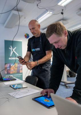 Zwei Frauen beugen sich über einen Tisch und füllen gemeinsam Unterlagen aus.