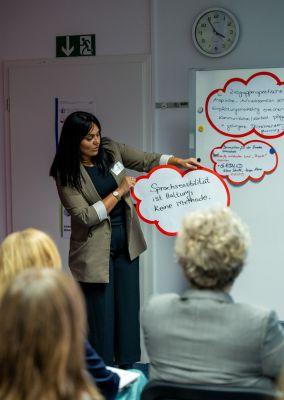 Zwei Personen betrachten eine Wand mit Fotos, Texten und QR-Codes aus dem Projekt #ABCforJobs.