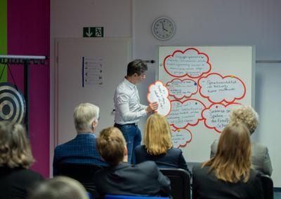 Eine Person hält ein Tablet und testet eine digitale Lernanwendung mit einem Sonnensymbol auf dem Bildschirm.