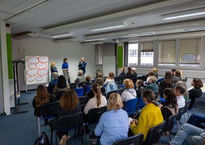 Zwei Personen betrachten eine Wand mit Fotos, Texten und QR-Codes aus dem Projekt #ABCforJobs.