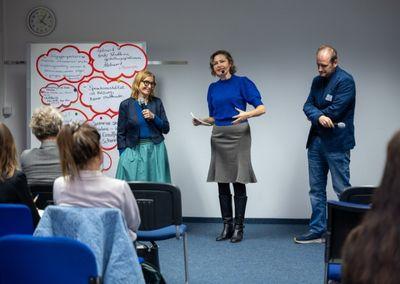 Zwei Personen betrachten eine Wand mit Fotos, Texten und QR-Codes aus dem Projekt #ABCforJobs.