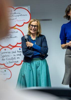 Eine Person hält ein Tablet und testet eine digitale Lernanwendung mit einem Sonnensymbol auf dem Bildschirm.