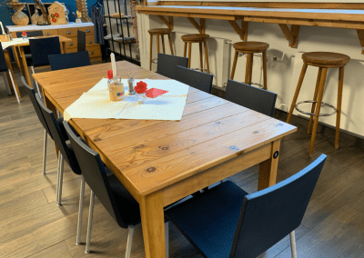 Gedeckter Holztisch im World Café mit roten Rosen, Kerze und Gewürzen.
